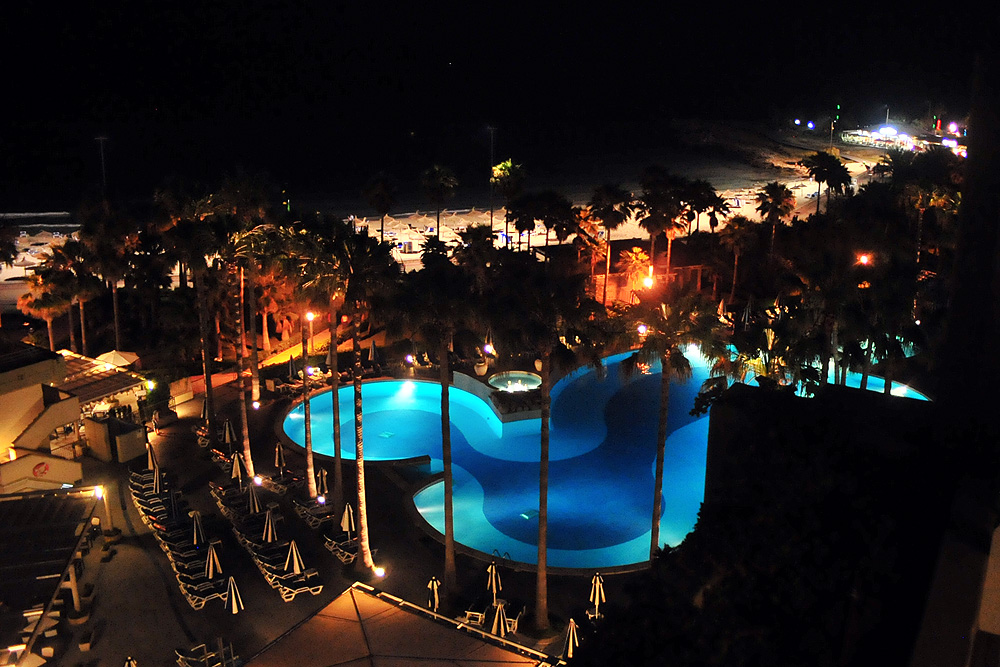 am ersten Abend aufgenommener Blick vom Balkon des Hotelzimmers auf den Pool und den Strand
